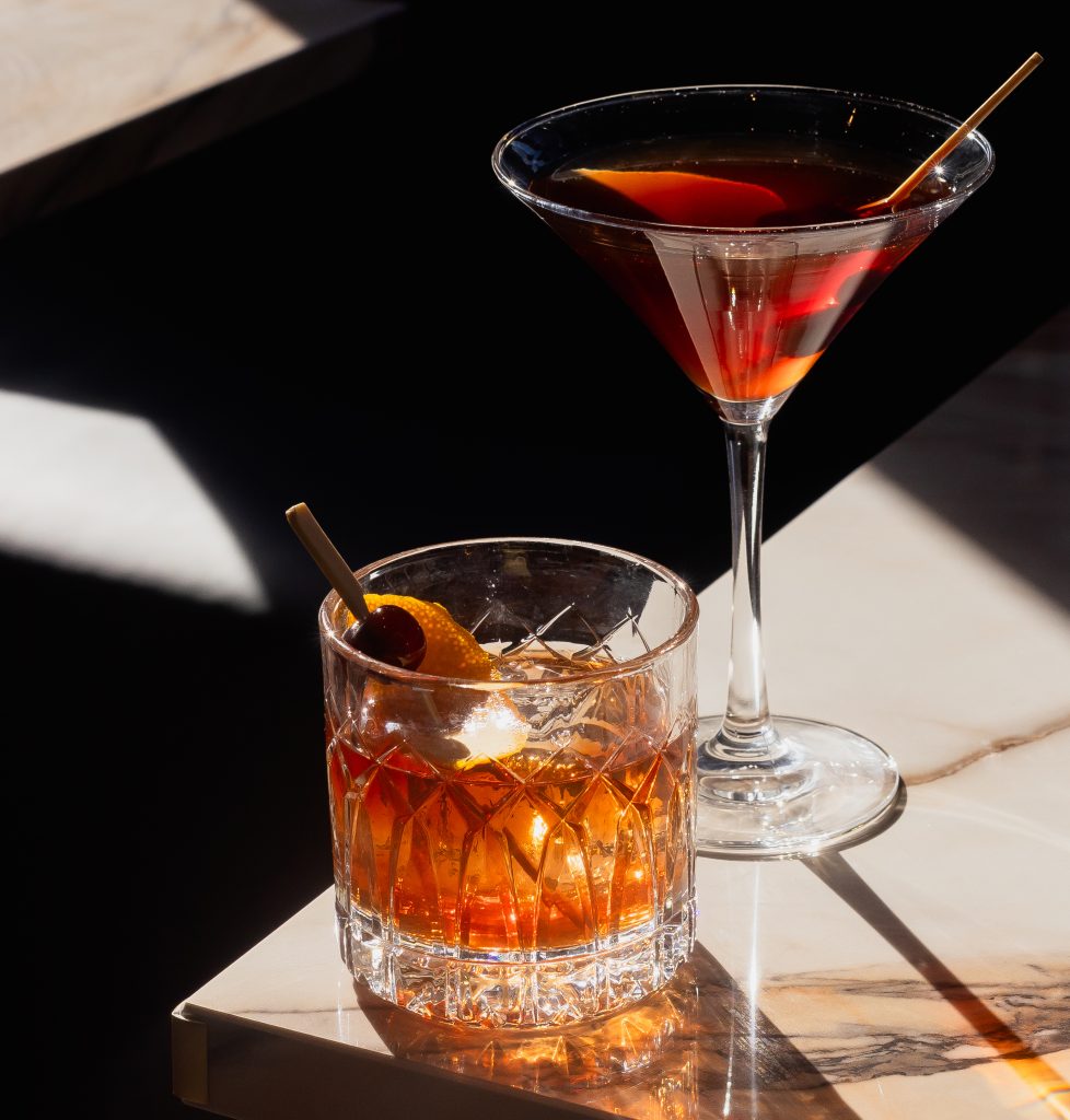 close up shot of two cocktails sitting on the edge of a table