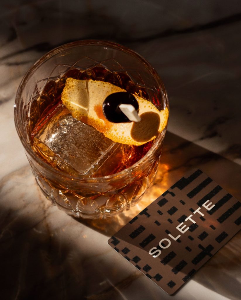 overhead shot of a cocktail bathed in sunlight casting a shadow against a solette gift card
