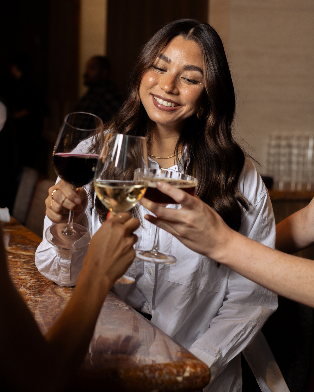 Close up shot of a woman clinking her wine glass with two other women