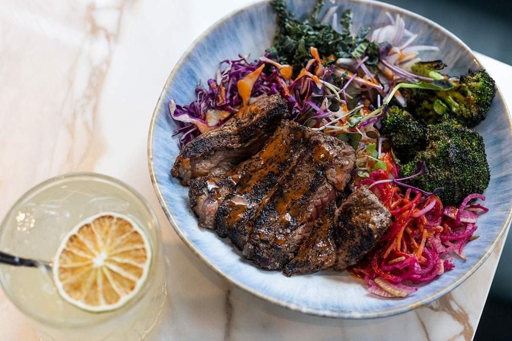 close up shot of a steak bowl and a cocktail